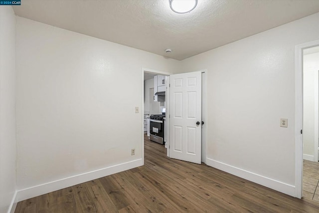 spare room featuring a textured ceiling and hardwood / wood-style flooring