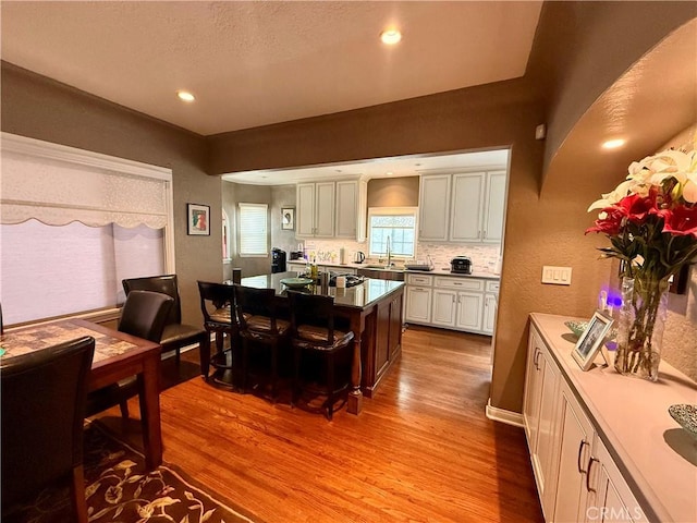 kitchen with white cabinets, decorative backsplash, light hardwood / wood-style floors, and sink