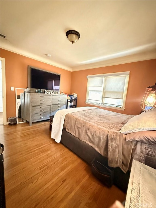 bedroom with ornamental molding and hardwood / wood-style flooring