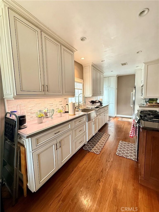 kitchen with stainless steel appliances, hardwood / wood-style flooring, tasteful backsplash, and sink