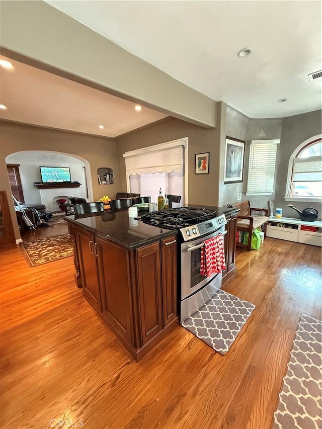 kitchen with gas stove, light hardwood / wood-style flooring, and dark stone countertops