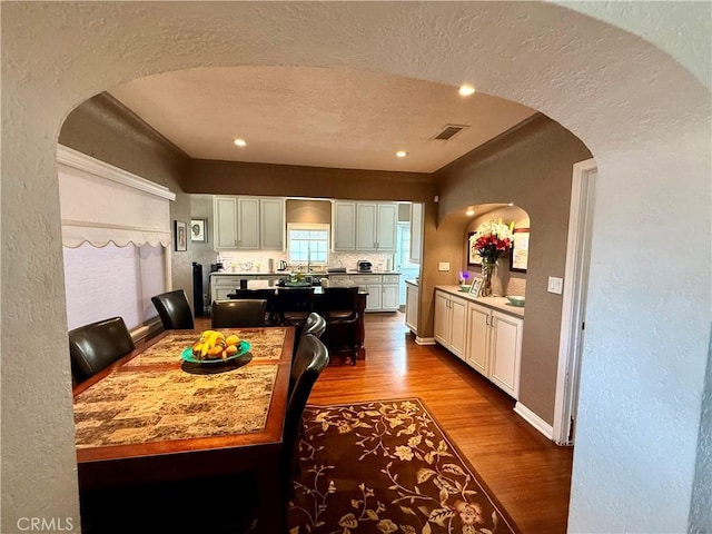 kitchen with white cabinets, tasteful backsplash, a textured ceiling, and light hardwood / wood-style flooring