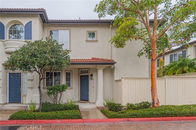 mediterranean / spanish-style house featuring fence, a tile roof, and stucco siding