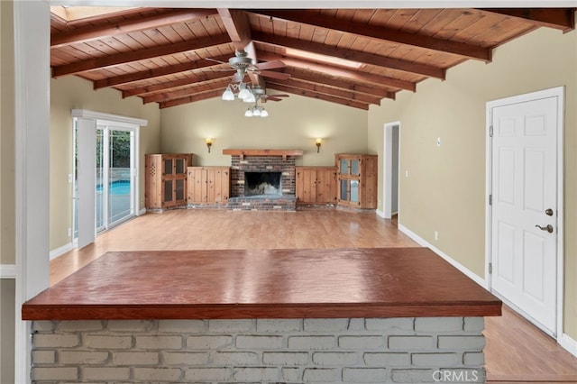 unfurnished living room featuring ceiling fan, vaulted ceiling with beams, light hardwood / wood-style flooring, a fireplace, and wood ceiling