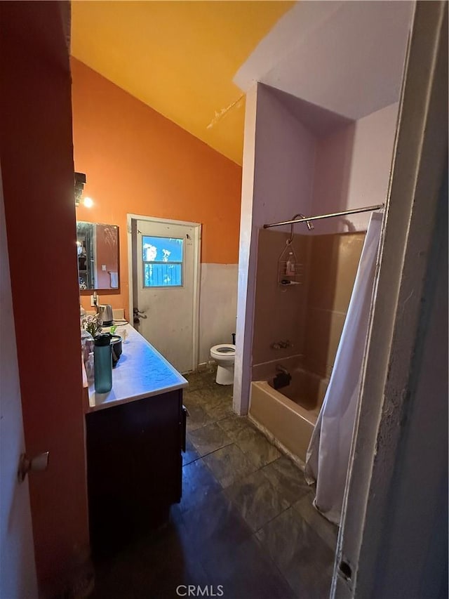 full bathroom featuring toilet, vaulted ceiling, vanity, and shower / tub combo with curtain