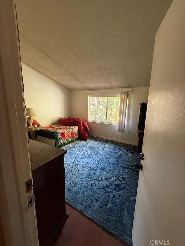 bedroom with dark hardwood / wood-style flooring and a textured ceiling