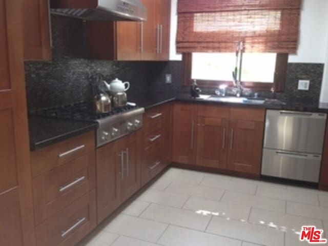 kitchen with tasteful backsplash, stainless steel appliances, sink, and dark stone counters