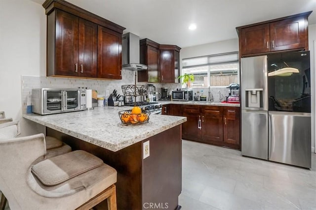 kitchen with a breakfast bar, backsplash, sink, wall chimney exhaust hood, and stainless steel appliances