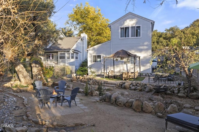 rear view of property featuring a gazebo, an outdoor fire pit, and a patio