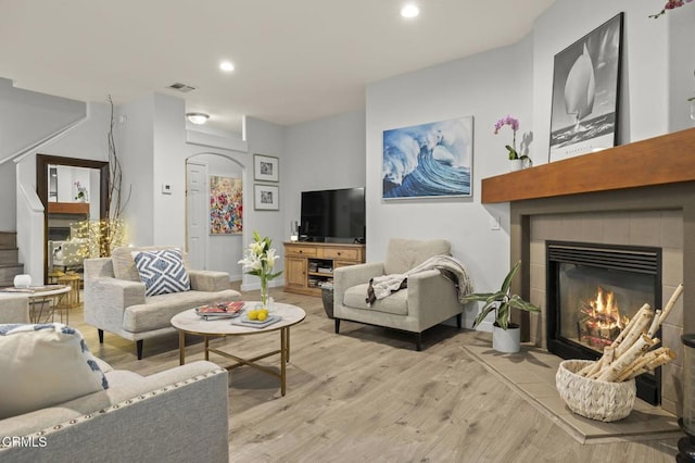 living room featuring light hardwood / wood-style flooring and a tiled fireplace