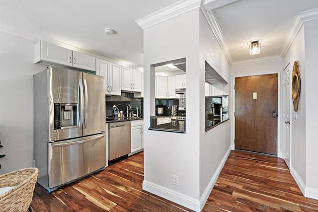 kitchen with appliances with stainless steel finishes, decorative backsplash, dark hardwood / wood-style floors, crown molding, and white cabinets