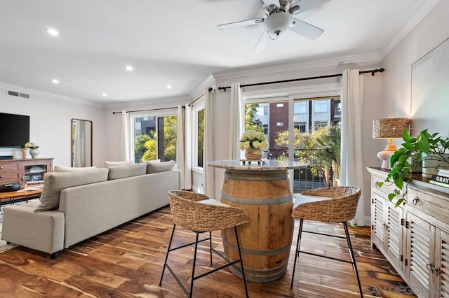 interior space with ceiling fan, dark wood-type flooring, and ornamental molding