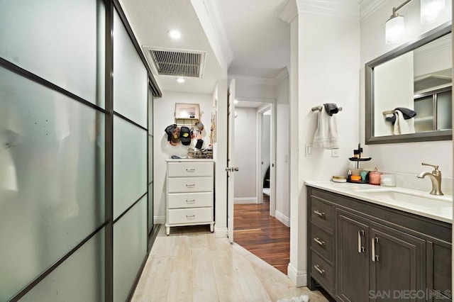 bathroom featuring vanity, crown molding, and hardwood / wood-style floors