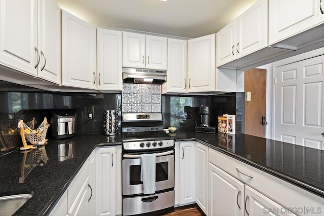 kitchen with stainless steel stove, dark stone countertops, white cabinets, and backsplash