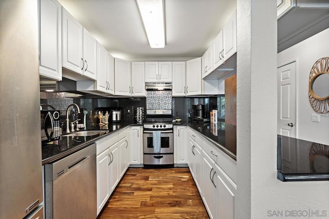 kitchen with appliances with stainless steel finishes, dark hardwood / wood-style floors, tasteful backsplash, white cabinets, and sink