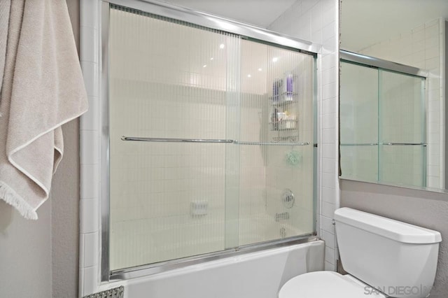 bathroom featuring bath / shower combo with glass door and toilet