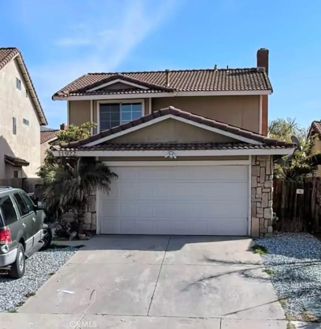 traditional-style home featuring a tile roof, driveway, a chimney, and fence