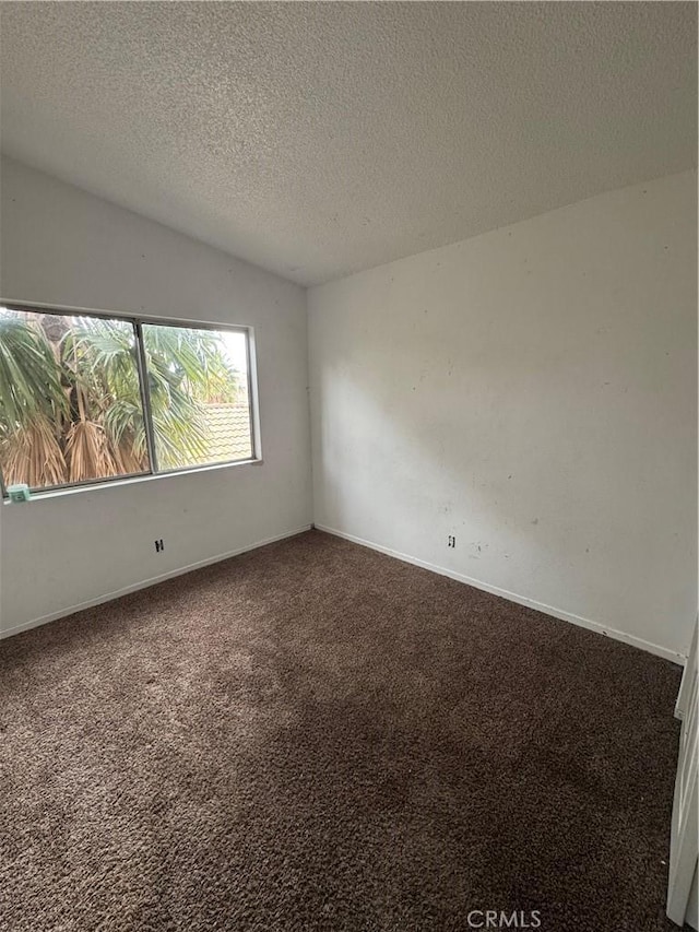 unfurnished room with carpet, vaulted ceiling, a textured ceiling, and baseboards