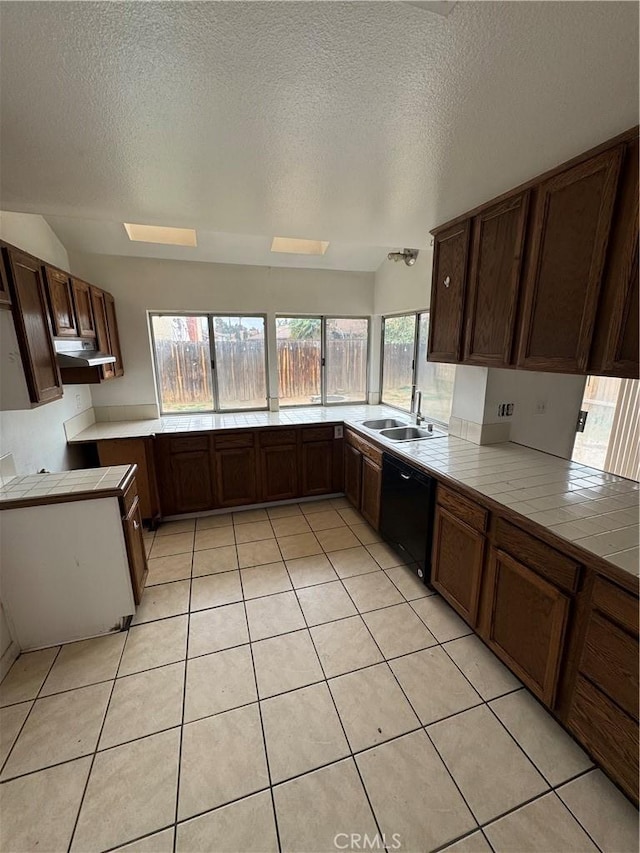 kitchen with black dishwasher, light tile patterned flooring, a sink, and tile countertops