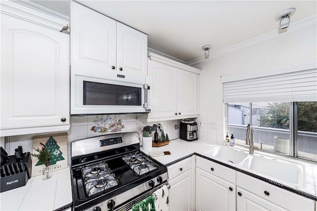 kitchen featuring decorative backsplash, ornamental molding, gas stove, sink, and white cabinetry