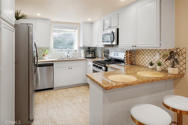 kitchen with kitchen peninsula, light stone countertops, sink, and stainless steel appliances