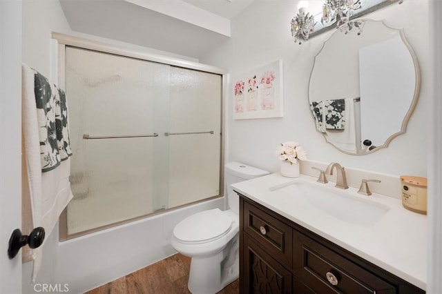 full bathroom with hardwood / wood-style floors, vanity, toilet, and combined bath / shower with glass door