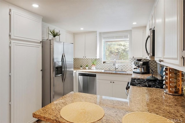 kitchen with white cabinetry, sink, backsplash, kitchen peninsula, and appliances with stainless steel finishes