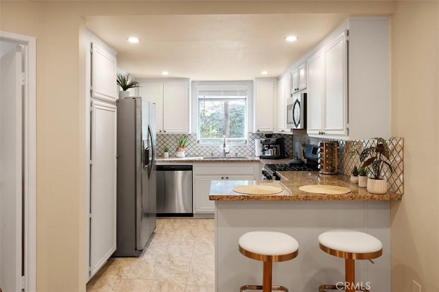 kitchen with kitchen peninsula, sink, white cabinets, and appliances with stainless steel finishes