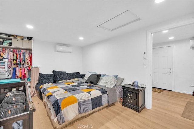 bedroom with light hardwood / wood-style floors and a wall mounted air conditioner