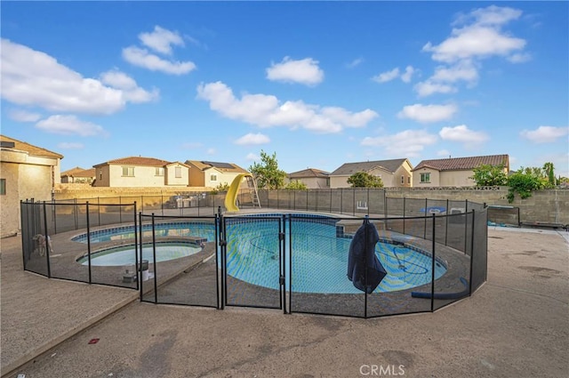 view of swimming pool with an in ground hot tub and a water slide