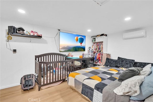 bedroom with light hardwood / wood-style floors and a wall unit AC