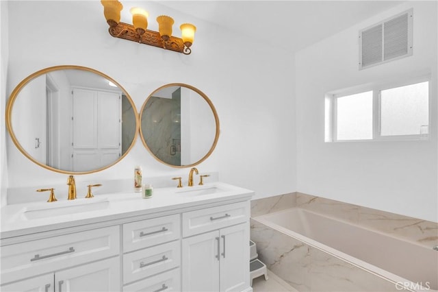 bathroom featuring tiled tub and vanity