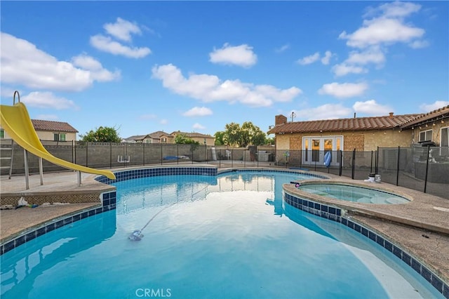 view of swimming pool with an in ground hot tub and a water slide