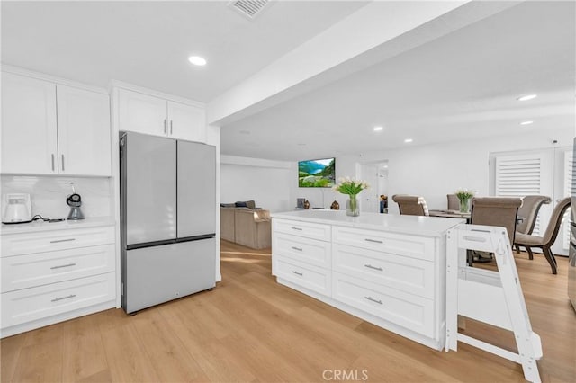 kitchen with backsplash, white cabinets, light wood-type flooring, and white refrigerator