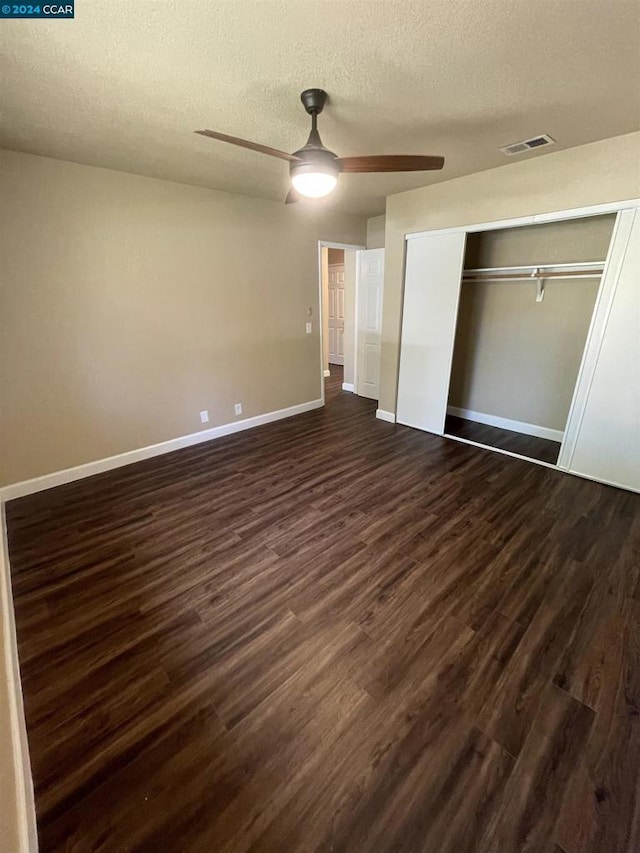 unfurnished bedroom featuring a textured ceiling, ceiling fan, dark wood-type flooring, and a closet