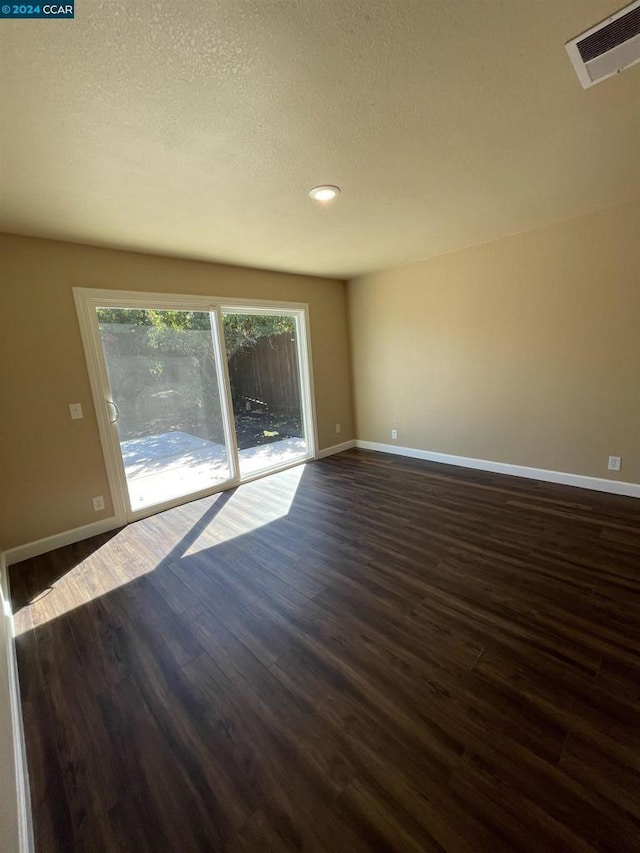 unfurnished room featuring a textured ceiling and dark hardwood / wood-style floors