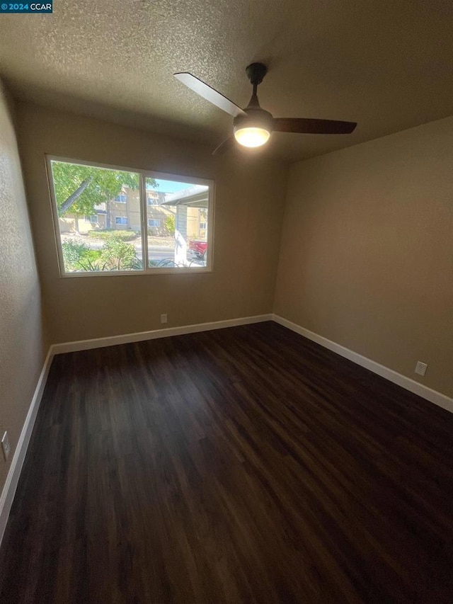 spare room featuring ceiling fan, dark hardwood / wood-style flooring, and a textured ceiling