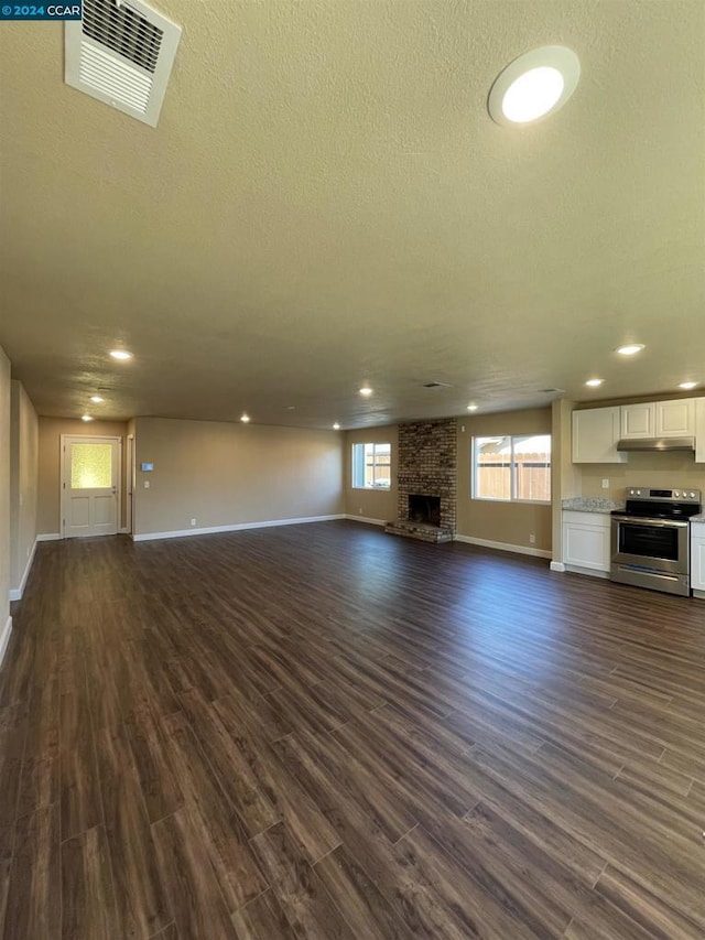 unfurnished living room featuring a large fireplace, dark wood-type flooring, and a textured ceiling