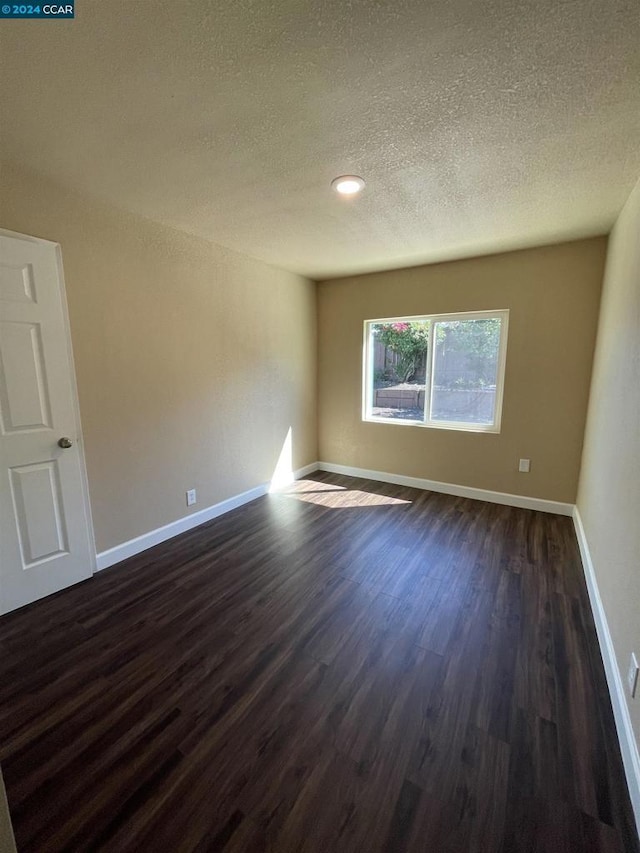 spare room with dark hardwood / wood-style floors and a textured ceiling