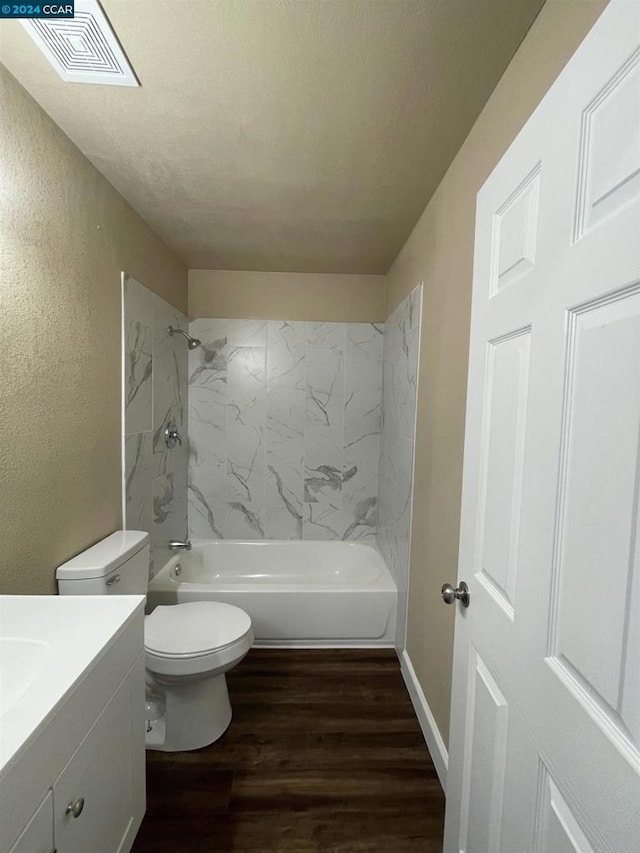 full bathroom with hardwood / wood-style floors, vanity, tiled shower / bath, toilet, and a textured ceiling