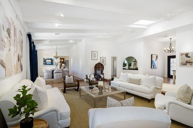 living room with beamed ceiling, light wood-type flooring, a skylight, and an inviting chandelier