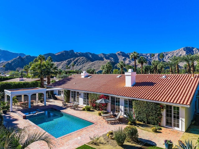 back of house with a mountain view, a pool with hot tub, a patio, and french doors