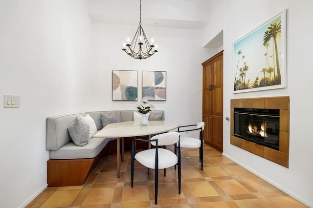 tiled dining space with breakfast area, an inviting chandelier, and a tiled fireplace