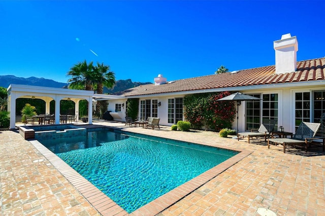 view of swimming pool featuring a mountain view, a patio area, and an in ground hot tub