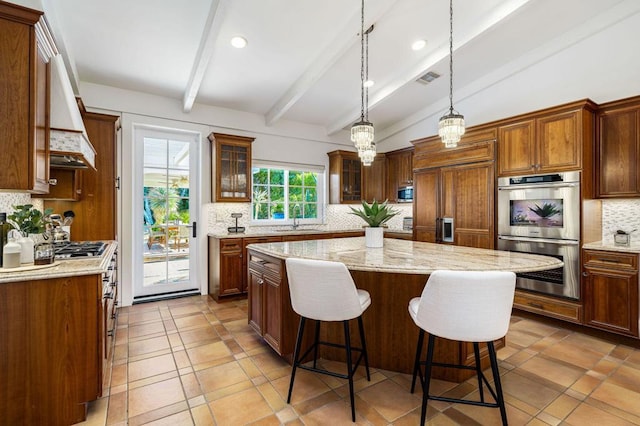 kitchen with vaulted ceiling with beams, appliances with stainless steel finishes, tasteful backsplash, decorative light fixtures, and a kitchen island