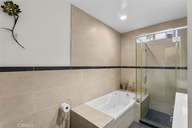 bathroom featuring tile walls and independent shower and bath