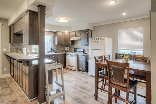 kitchen featuring tasteful backsplash, white appliances, sink, and light hardwood / wood-style floors