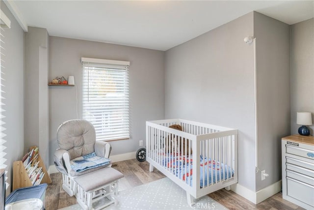 bedroom with a nursery area and light hardwood / wood-style flooring