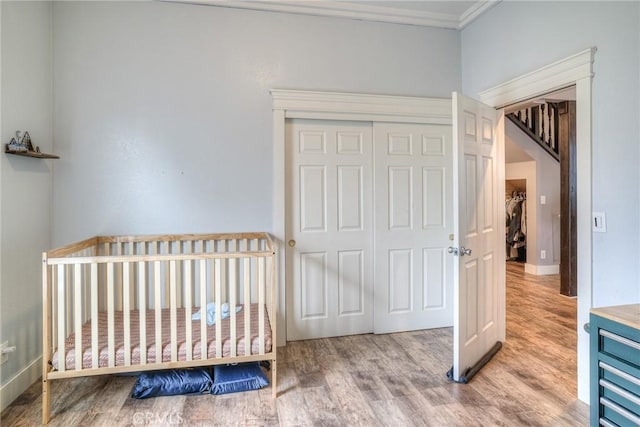 bedroom featuring crown molding, hardwood / wood-style floors, and a closet