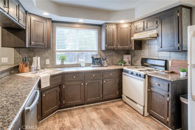 kitchen with light hardwood / wood-style flooring, dishwasher, backsplash, dark brown cabinets, and white gas range